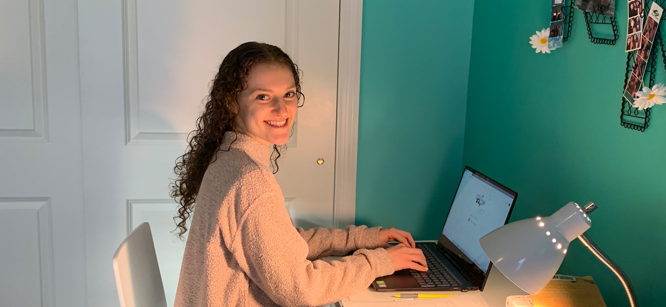 Photo of female student smiling and working on a laptop