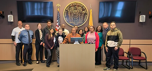 A diverse group of people stands together in front of a podium, engaged in conversation or awaiting a presentation