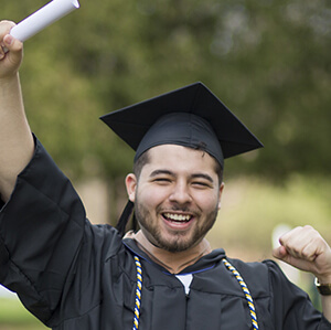 Headshot of Isaac Salazar wearing a graduation gown, smiling as he celebrates his academic achievement