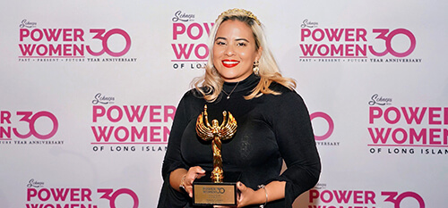 A woman proudly holds an award, celebrating her recognition as a powerful figure among women in her field