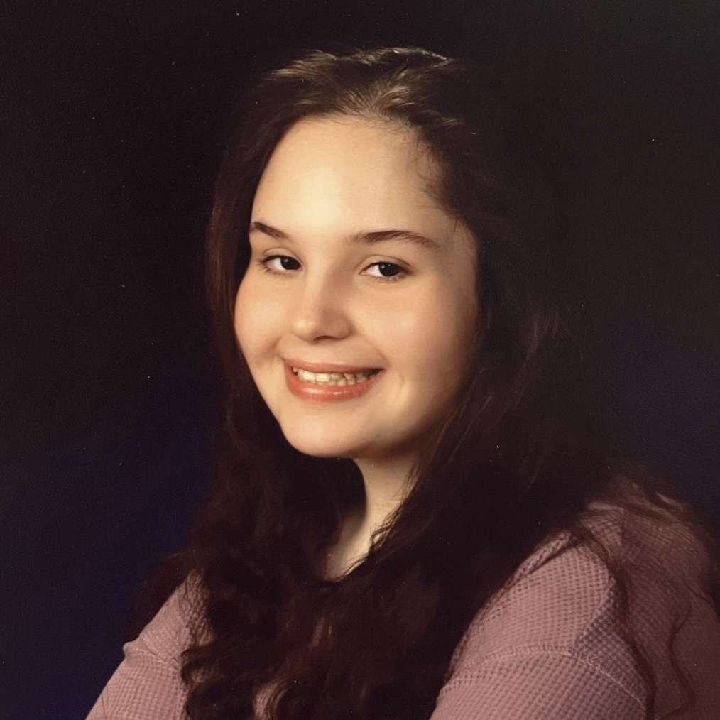 Berkeley graduate cassie servitis poses in a pink top with a dark background