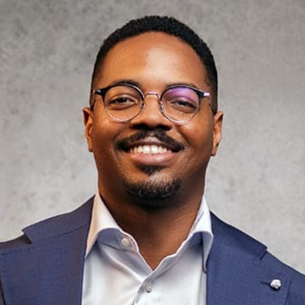 Berkeley Alumnus Rui Oliviera stands with a blue suit and lapel pin