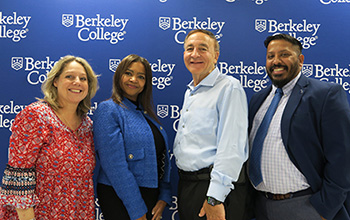 Four people standing in front of a blue Berkeley College backdrop, dressed in business and casual attire.