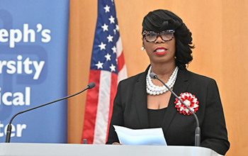 A woman in black and red speaks at a podium