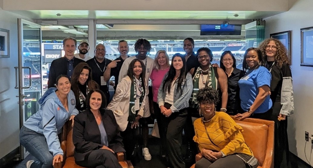 A group of diverse people smile and pose for a camera.