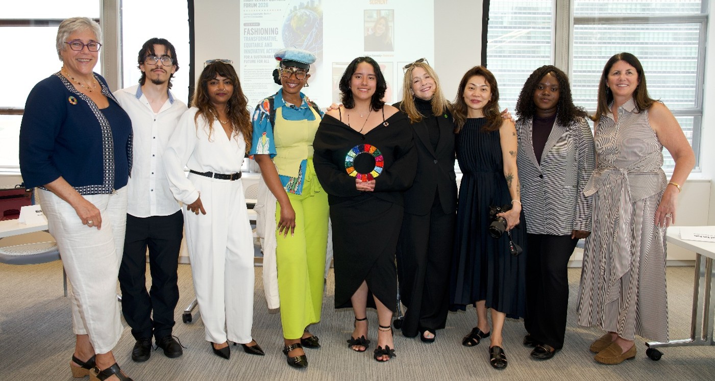 A group of diverse people stand in a line and smile for the camera at a United Nations event.