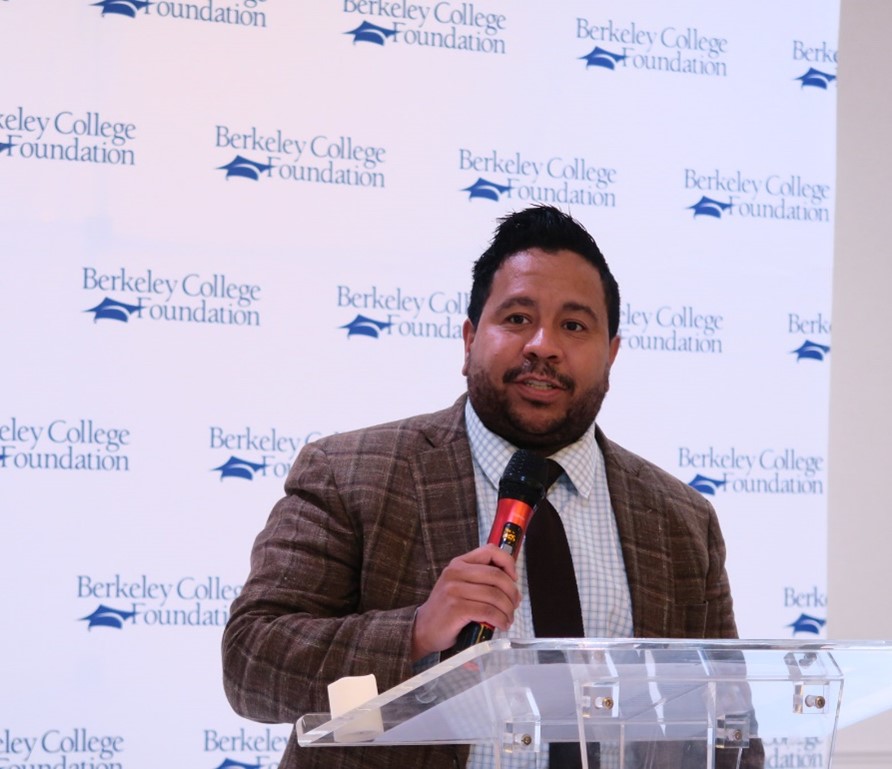 A man stands at a podium holding a microphone and gives a speech