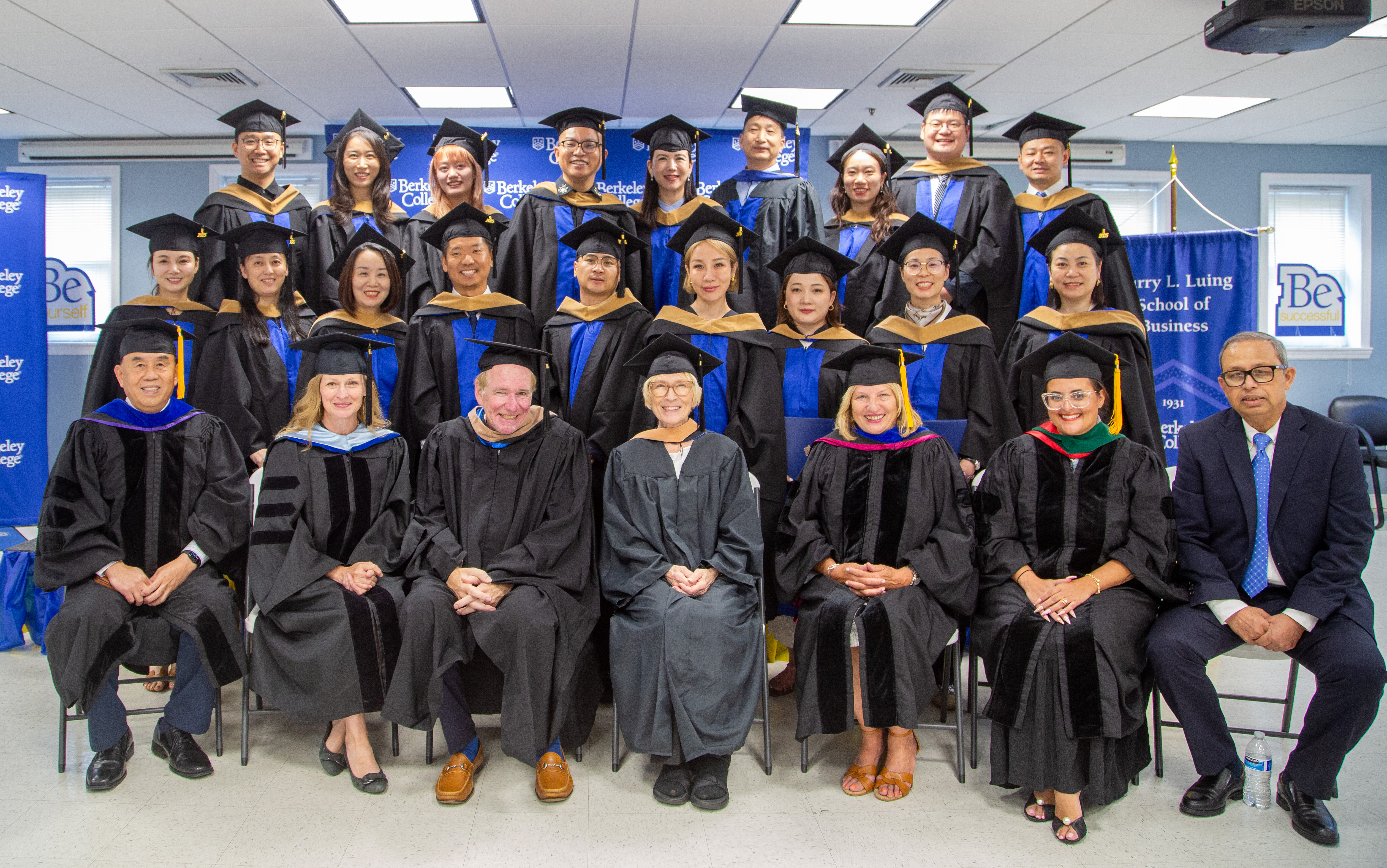 Students and faculty in graduation robes smiling at a graduation ceremony