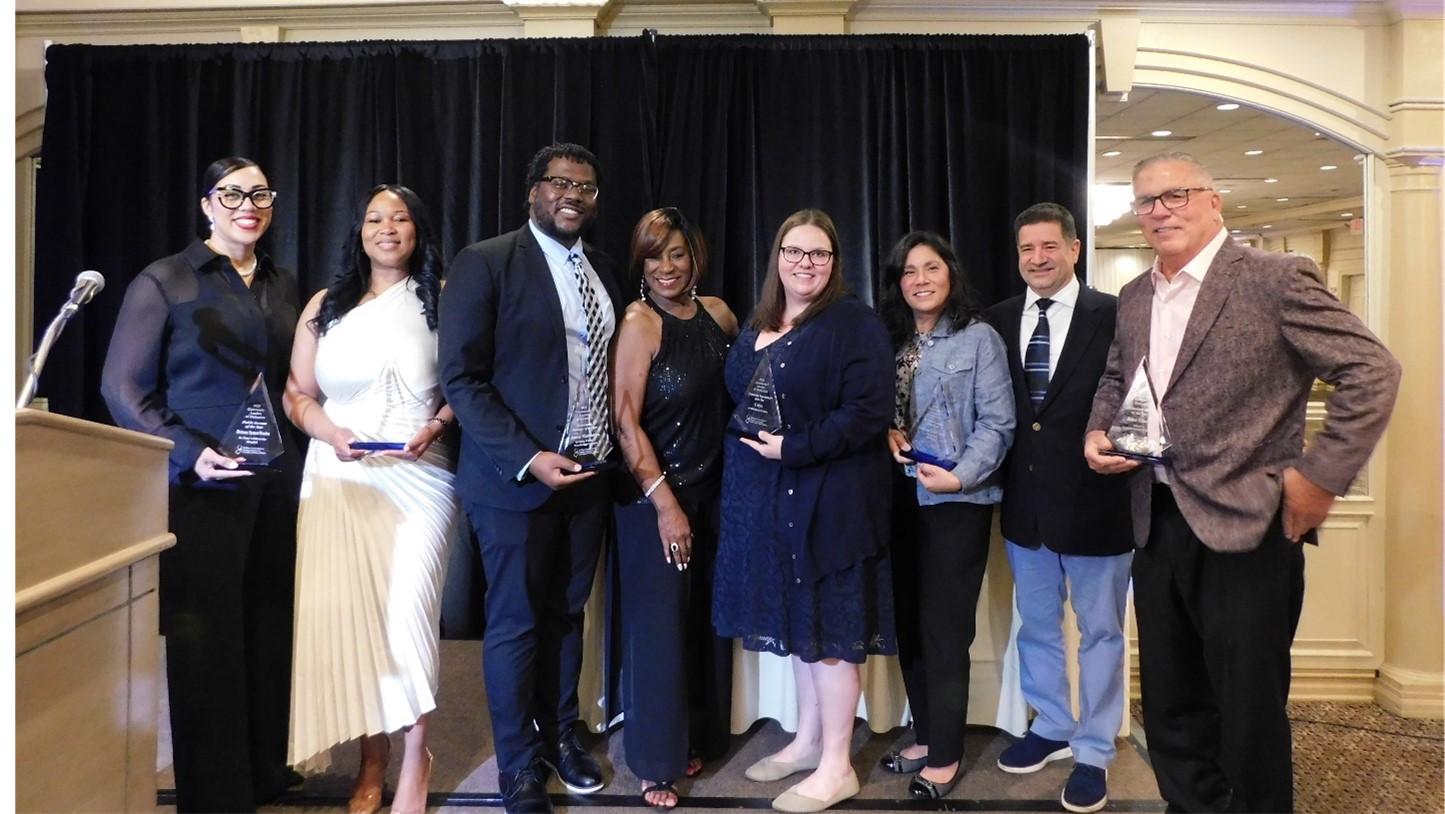 A group of honorees stands and smiles with their awards