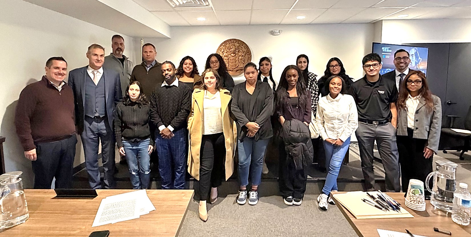 Students and lawyers pose and smile for the camera in a mock courtroom.