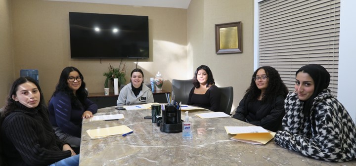 Students sit at a table and smile.