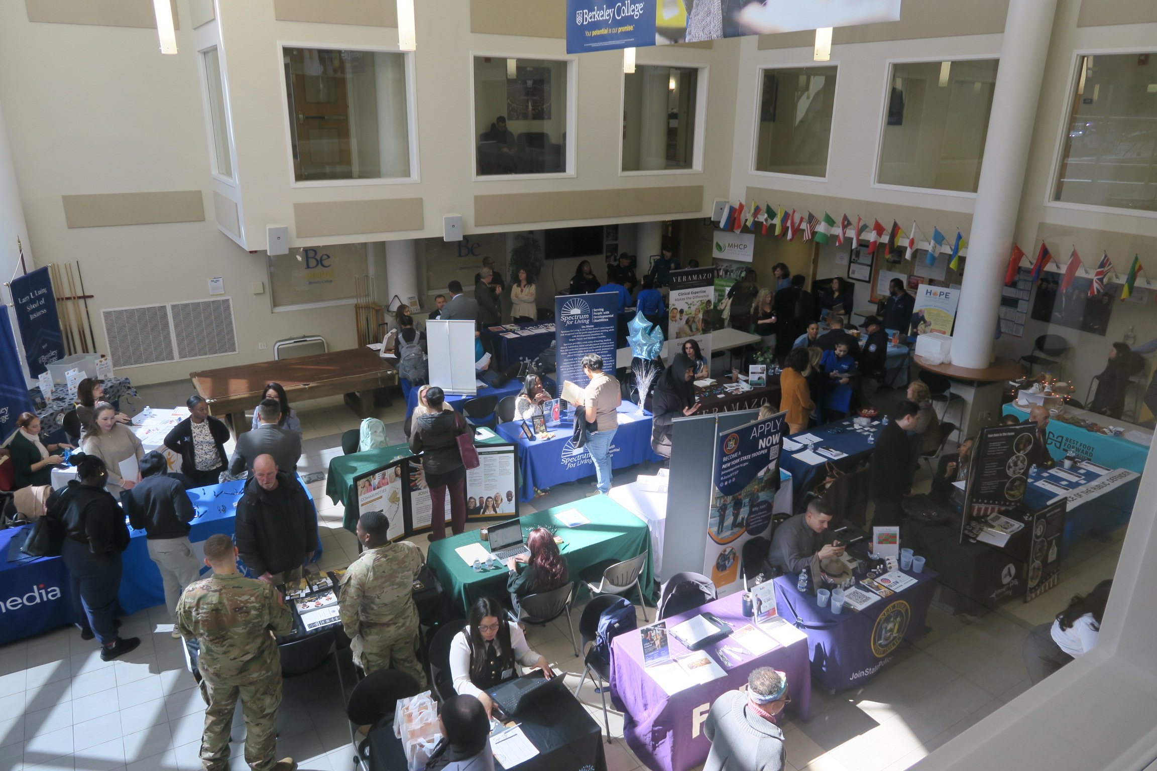 An auditorium filled with people, tables, and posters.